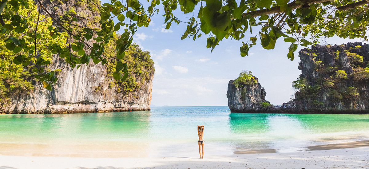 woman wades into the water at a beach on a tropical island